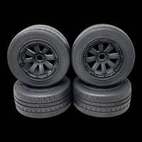 Four black model car wheels with detailed treads on a transparent background