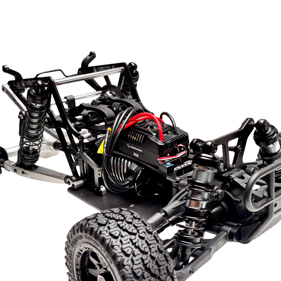 Close-up of a black and silver RC car chassis with visible components on a white background
