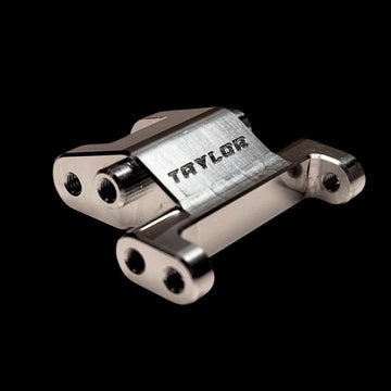 A silver billet front suspension mount with the brand name 'Taylor' engraved on it.