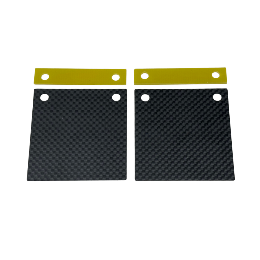 Two black carbon fiber plates with gold straps on a white background